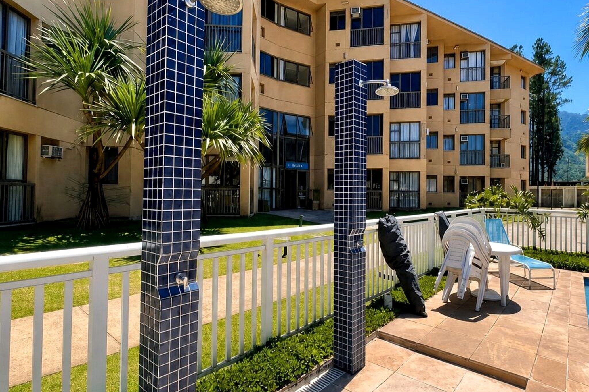 Um hotel com área de piscina, espaço para sentar ao ar livre e um jardim bem cuidado.