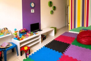 Ein Spielzimmer für Kinder mit einer weißen Unterhaltungseinheit, bunten Spielsachen und einem großen Sitzsack.