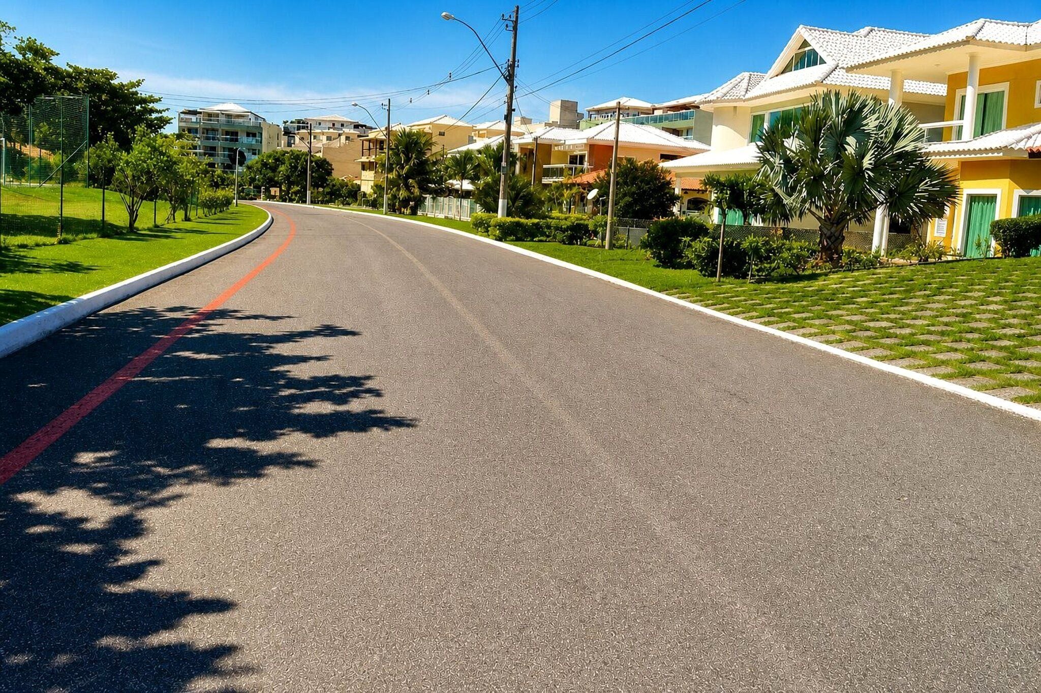 Rua residencial com casas, uma estrada sinuosa e calçada.