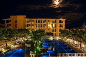 Un hôtel doté d’une piscine, de palmiers et offrant une vue sur le ciel nocturne.