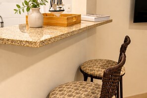 A kitchen counter with a vase, a wooden box, and a book. Below the counter, there are two chairs with patterned upholstery. - Reserva do Sahy, Condado (Mangaratiba)
