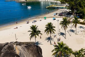 Une plage bordée de palmiers, une rive sablonneuse et des bateaux sur l’eau.