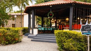 Un restaurant doté d’une terrasse, d’un chemin de gravier et d’une enseigne indiquant qu’il s’agit du restaurant Quintal Doc.