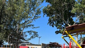 A playground with various play structures, a building in the background, and trees. - Reserva do Sahy, Condado (Mangaratiba)