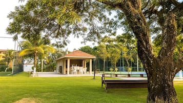 Um parque com um coreto, quadra de tênis e mesa de bilhar.