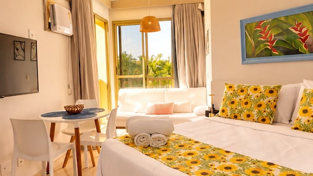 Ein Hotelzimmer mit einem Bett, einem Schreibtisch, einem Stuhl, einem fenster mit Vorhängen und einem Bild an der Wand.