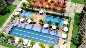 Ein Luftbild eines Hotels mit Schwimmbad, Liegestühlen und Palmen.