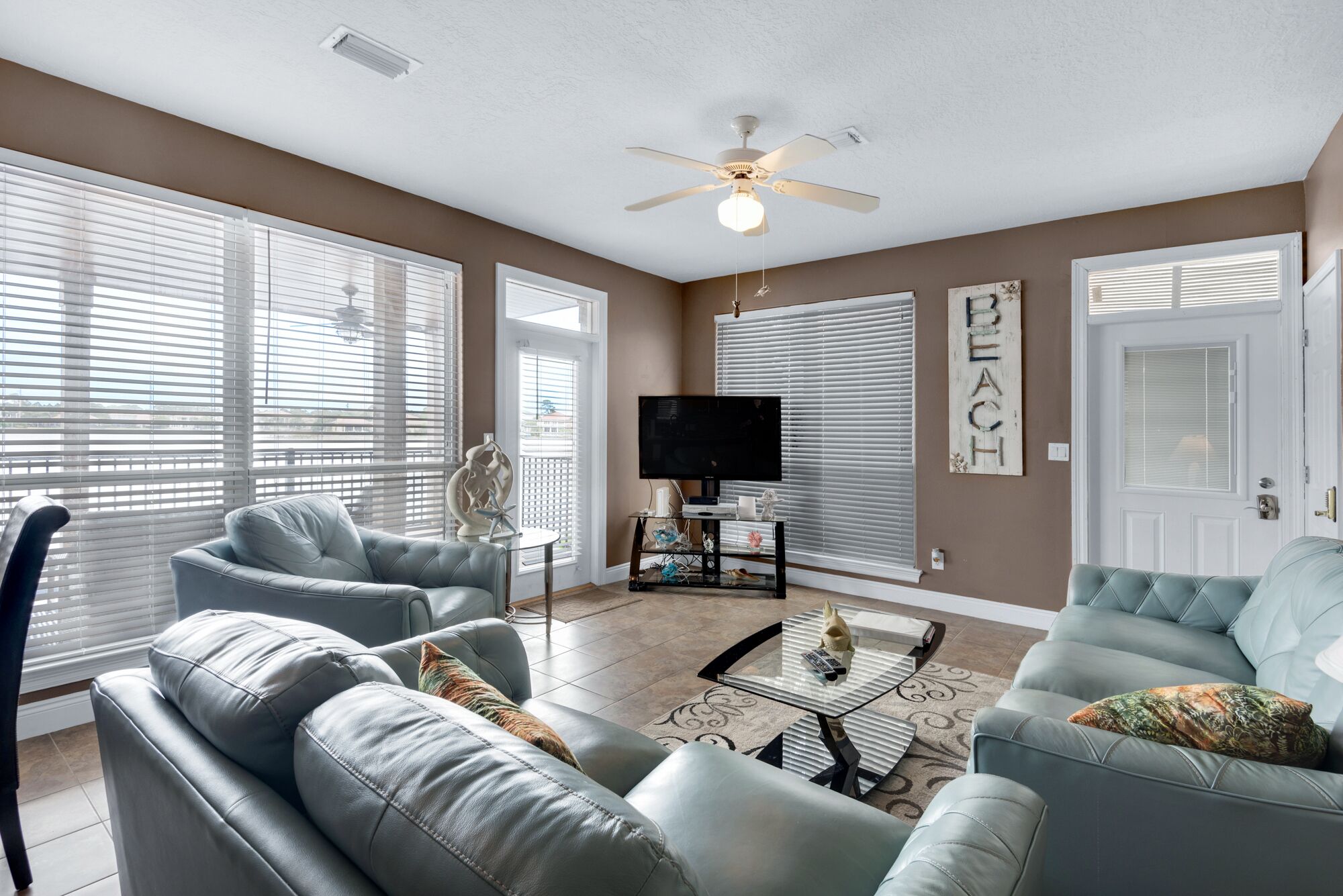 A living room with two grey sofas, a coffee table, a TV on a stand, and a ceiling fan.