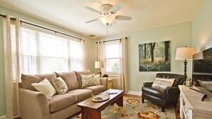 A living room with a beige sofa, a wooden coffee table, a black leather chair, and a floral rug. - Cottage Style guest house centralized in Lancaster County (Lancaster)