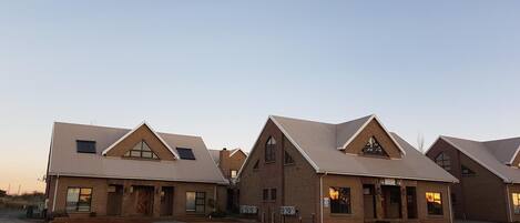 A row of modern buildings with pitched roofs and brick exteriors.