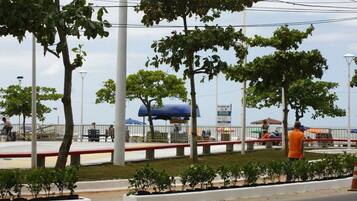 A public park with trees, a blue canopy, and a white fence.