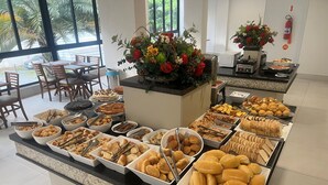 A buffet with various food items and a flower centerpiece. - Hotel das Américas (Balneário Camboriú)