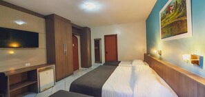 Una habitación de hotel con cama, televisor, escritorio y armario.