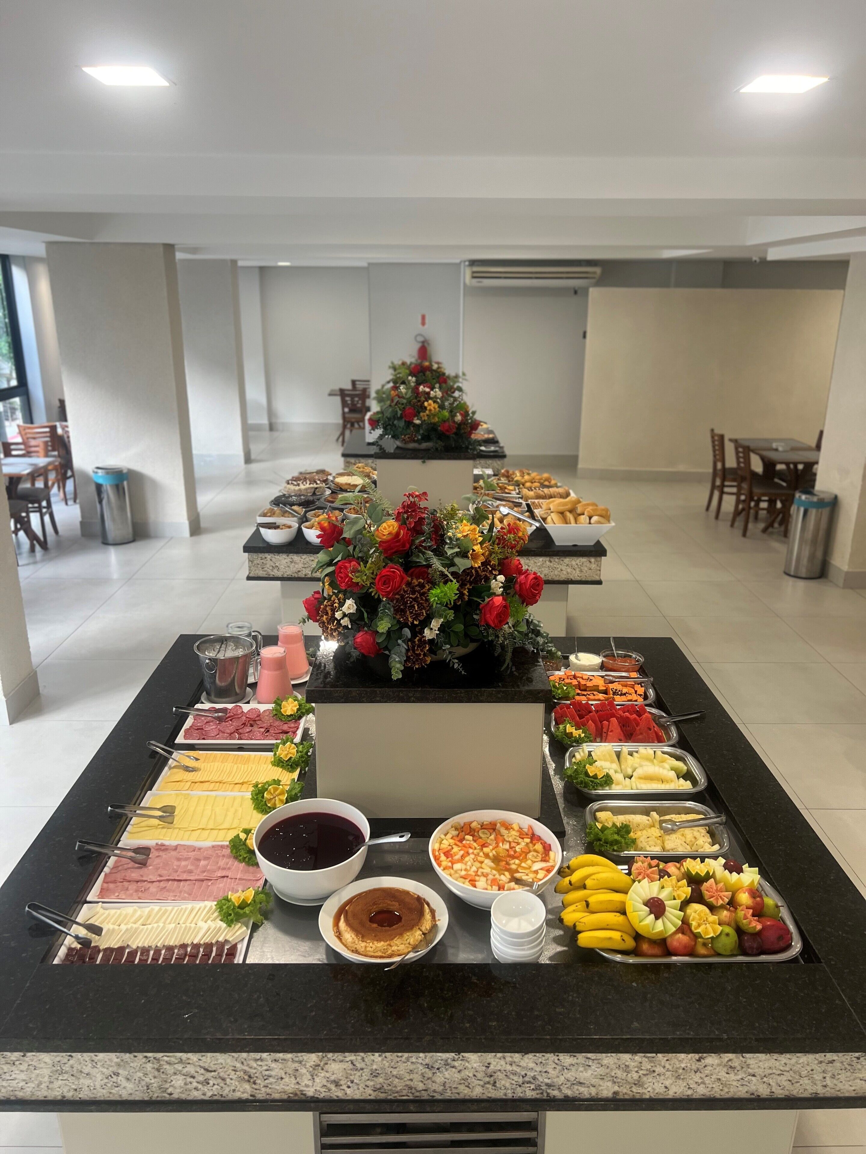 A buffet setup with various food items and a floral centerpiece.