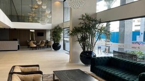 A spacious lobby with a modern design, featuring a large seating area with sofas and a coffee table, a large potted plant, and a view of the outside through large windows. - Hotel das Américas (Balneário Camboriú)