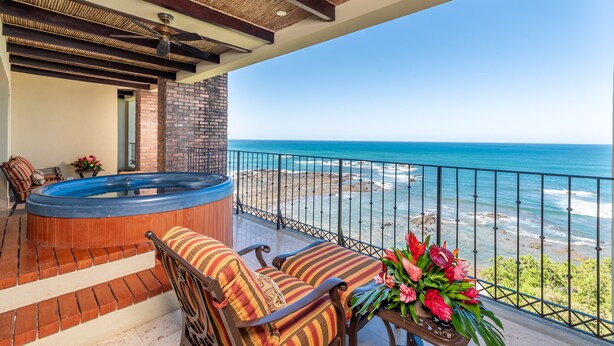 Un balcon avec un jacuzzi, des chaises et une vue sur l’océan.