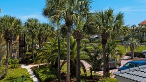 A residential area with palm trees, a pathway, and a building with a tiled roof. - Ocean view, walk to the beach, pool,  military/first responder discount 13A (Destin)