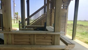 Un espacio de estar al aire libre con bancos de madera, suelo de hormigón y una escalera que sube a un nivel superior.