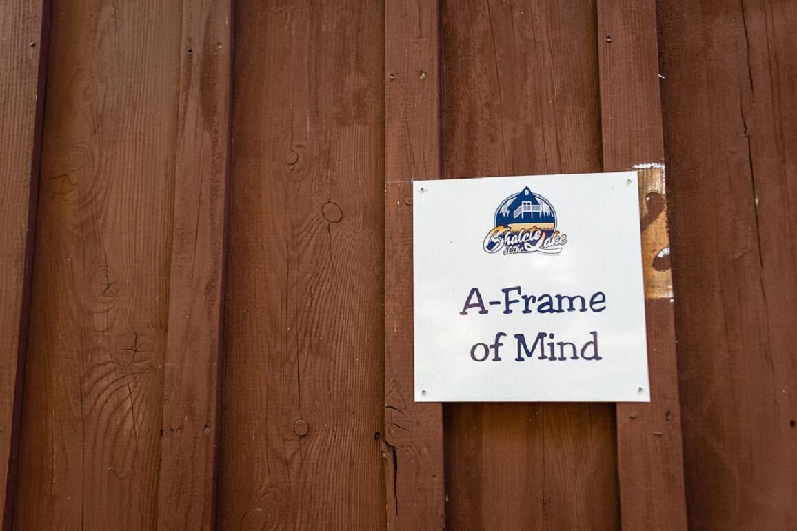 A wooden fence with a sign that reads 'A-Frame of Mind' and a logo.
