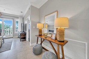 A modern living room with a wooden console table, two lamps, a mirror, and a view of the outdoors through a sliding glass door.