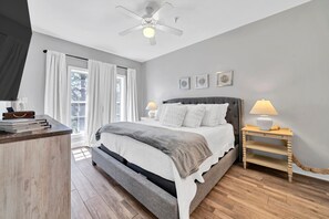 A bedroom with a bed, bedside tables, a ceiling fan, and a window with curtains.