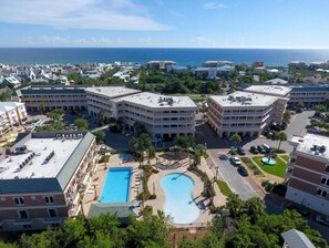 A hotel with multiple buildings, a swimming pool, and a view of the ocean.