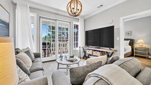 A modern living room with a sofa set, a coffee table, a TV, and a balcony with a view. - Overlooking 30A!  Great Location! Easy Beach & Pool Access! (Seacrest Beach)