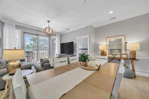 Relax in this stylish living room with a large dining table, comfortable sofa, and wall-mounted TV.