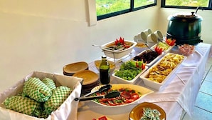 Una mesa de buffet con diversos alimentos y vista al océano a través de amplios ventanales.