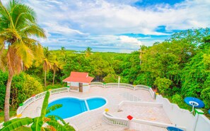A pool area with a curved design, surrounded by lush greenery and palm trees. - Hotel On Vacation Magic Hill (San Andrés)