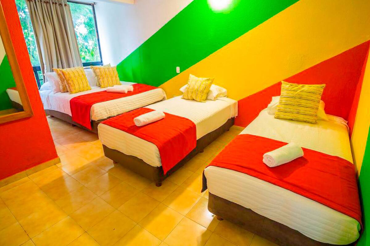 A hotel room with two beds, each with red and white bedding, and a green wall.