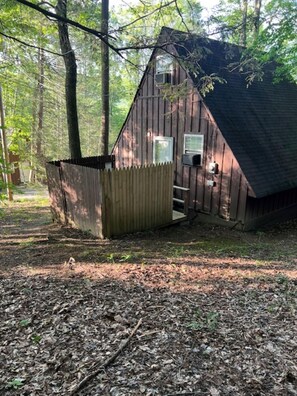 Une cabane rustique avec une façade en bois, un petit porche et une fenêtre.