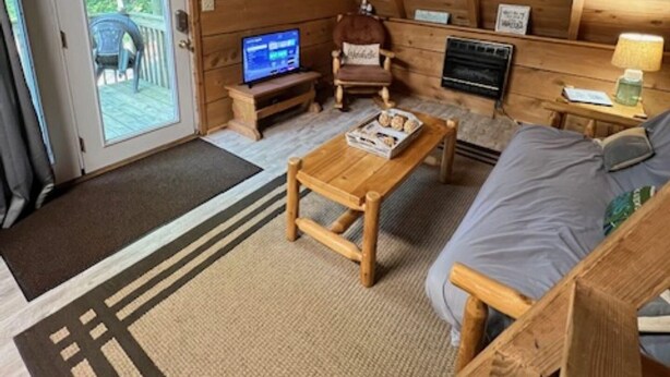 Ein gemütliches Blockhaus-Interieur mit Holzbalkendecke, einer Couch, einem Couchtisch, einem Fernseher und einem Schild mit der Aufschrift "The Lake".