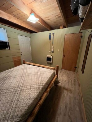 Une chambre à coucher avec un lit en bois, une fenêtre, une porte et un ventilateur de plafond.