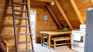 A wooden interior with a wooden table, bench, ladder, and white stove. - Reel Simple - Pet Friendly with Hot Tub (Summersville)