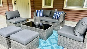 Eine Sitzgruppe im Freien aus Rattan mit Kissen und einem Couchtisch mit Glasplatte.