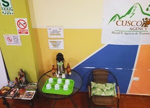 Guest rooms feature a unique green accent wall, a large poster, and a table with a selection of refreshments.