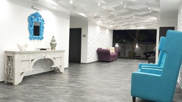 Un interior moderno con una consola blanca, una silla azul y un sillón morado.