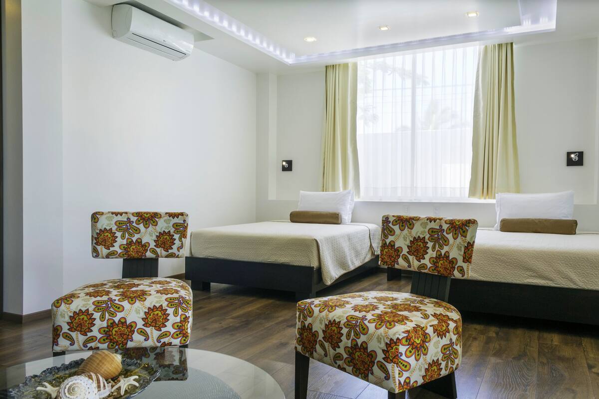 Une chambre d’hôtel avec deux lits, un canapé et une petite table agrémentée d’objets décoratifs.