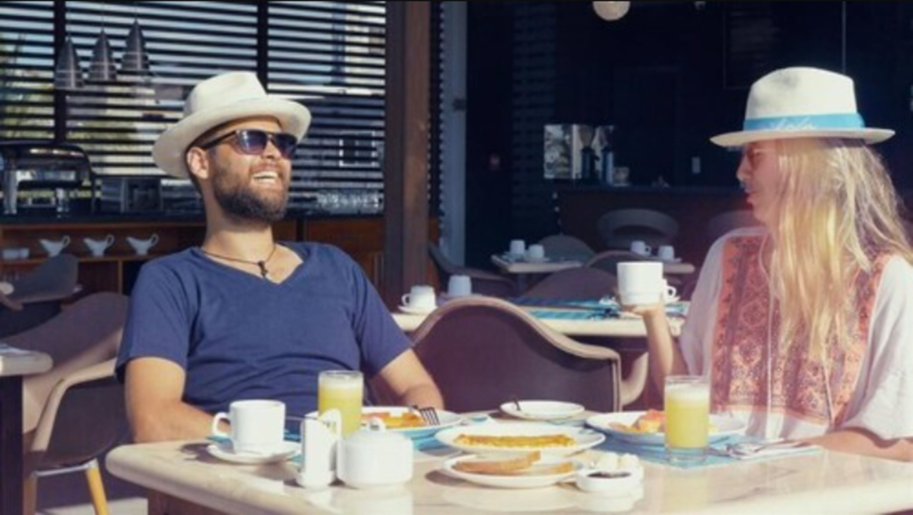 Un espace repas avec des tables et des chaises, une fenêtre avec des stores et une vue sur la rue.