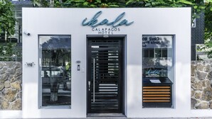 Exterior del Hotel Ikala Galapagos, con un diseño moderno, fachada de piedra y puerta de entrada negra.