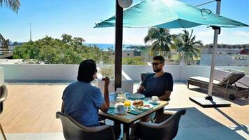 Two people dining at an outdoor table with a view of the beach and palm trees.