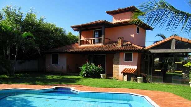 Ein zweistöckiges Haus mit einem Pool im Vorgarten.