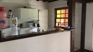 Eine Küche mit weißen Schränken, einer Mikrowelle, einer Kaffeemaschine und einem Fenster mit Blick nach draußen.