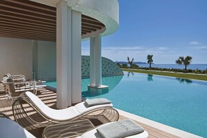 Zona junto a la piscina con sillones y vista al océano.