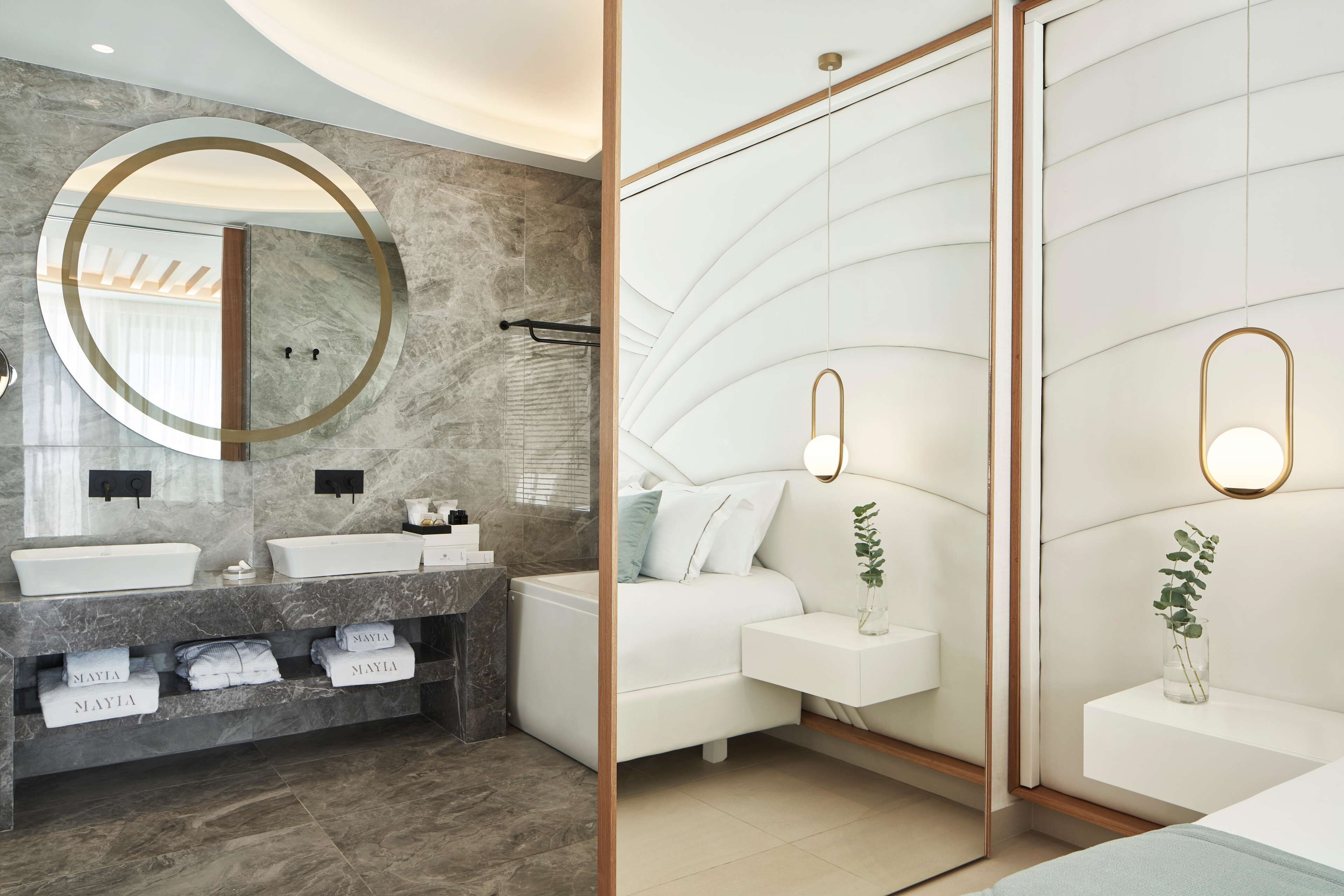 Un baño moderno con tocador doble, bañera y espejo grande con marco dorado.