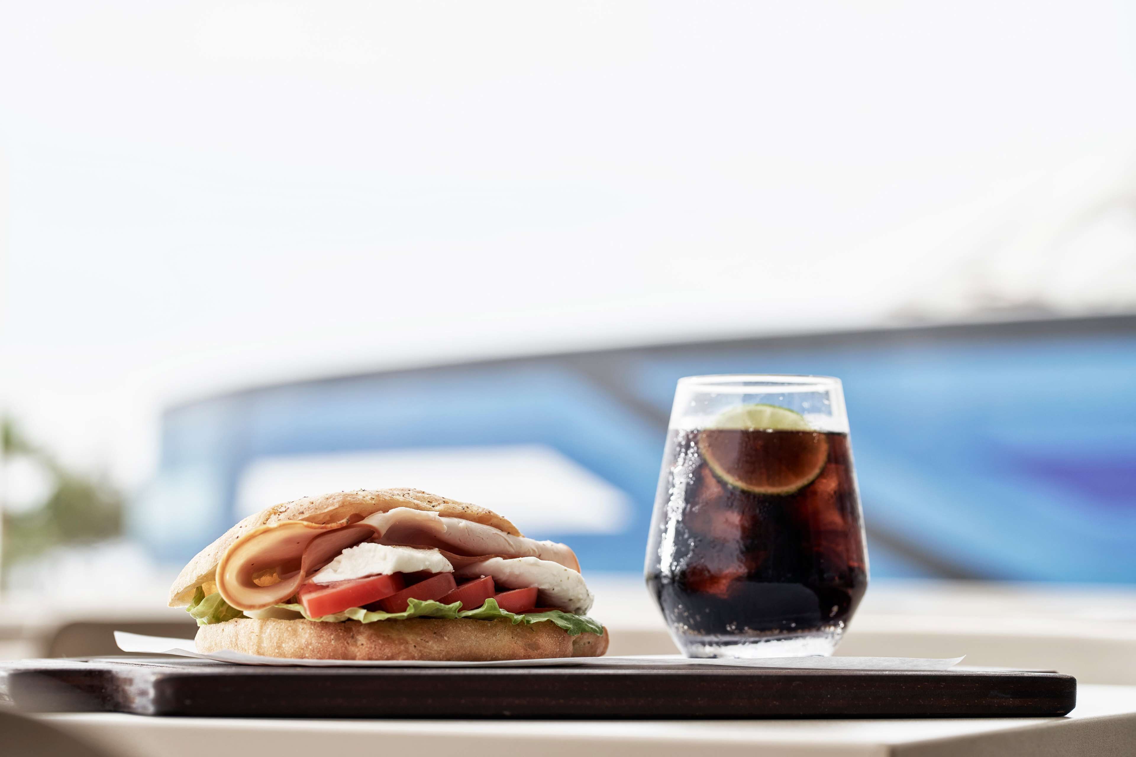 A sandwich and a glass of soda on a tray.