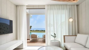 A modern living room with a TV, a sofa, a coffee table, and a view of a pool and ocean. - Mayia Exclusive Resort & Spa - Adults Only - All Inclusive (Rhodes)
