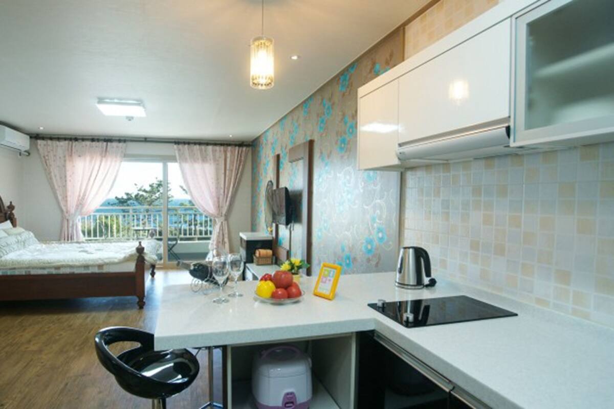 A compact room with a bed, kitchenette, and a dining area.