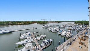 A marina with multiple boats docked, a clear sky, and a river in the background. - Waterfront Views | Boat-Friendly | Lazy River & Pools | On-site Dining (Orange Beach)